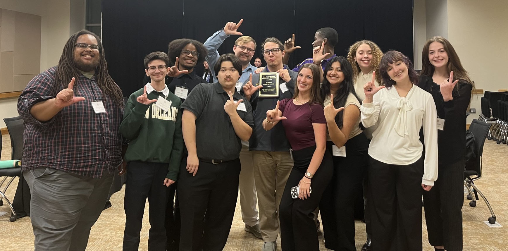 Group photo of team members showing an "L" hand signal 