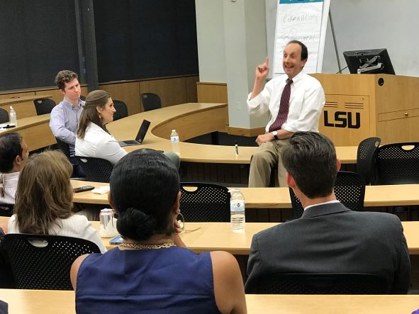 Tommy Karam sits on table as he lectures to class