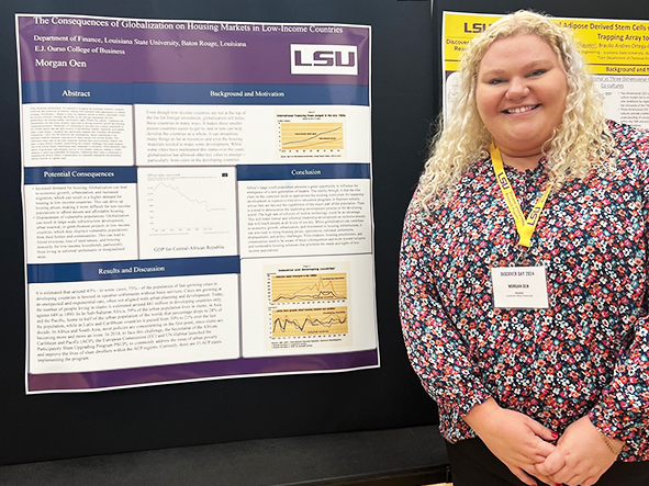 Morgan Oen stands in front of research poster. She is wearing a flower shirt. 