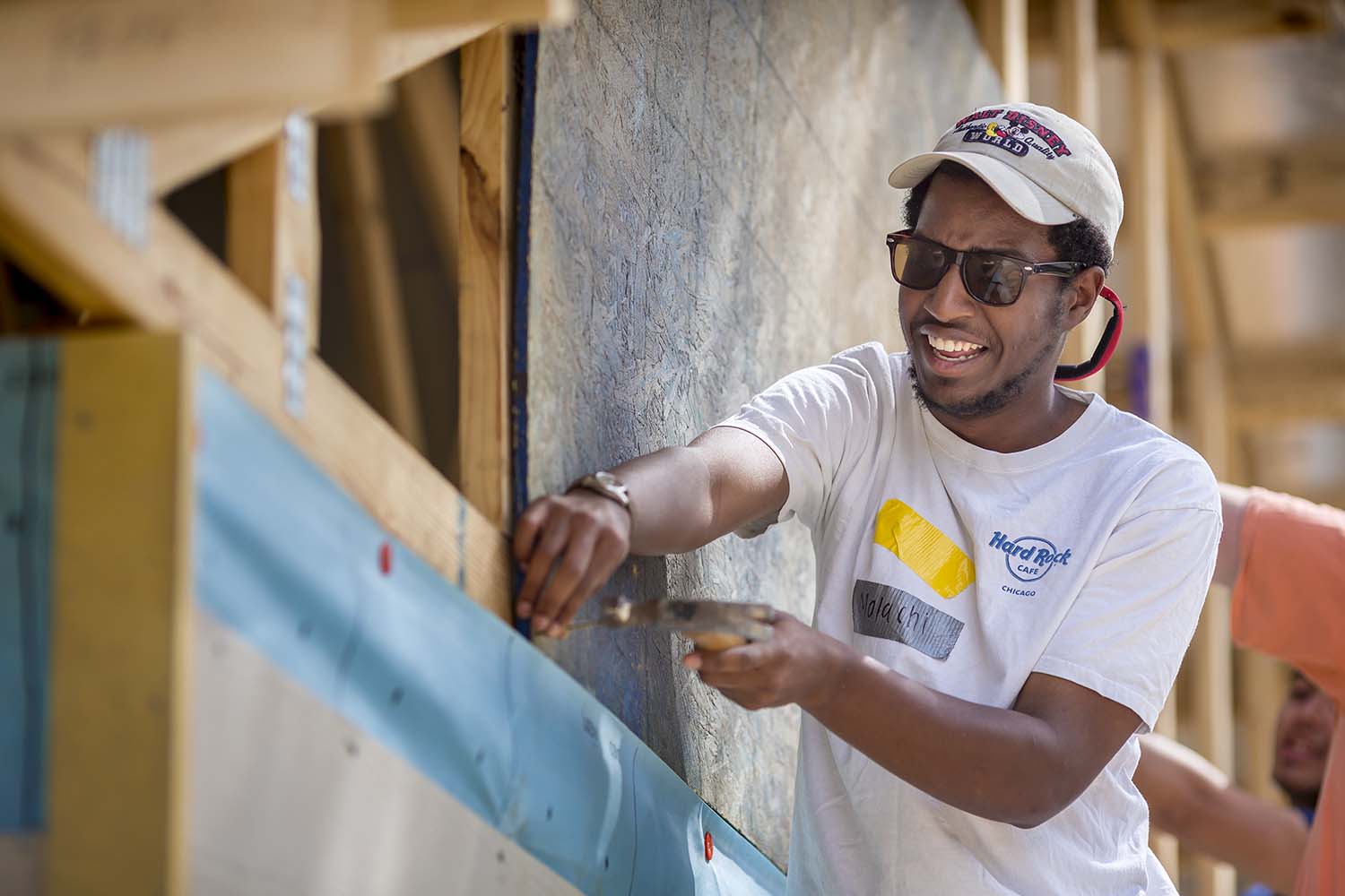 black man wearing baseball cap and working on a roof