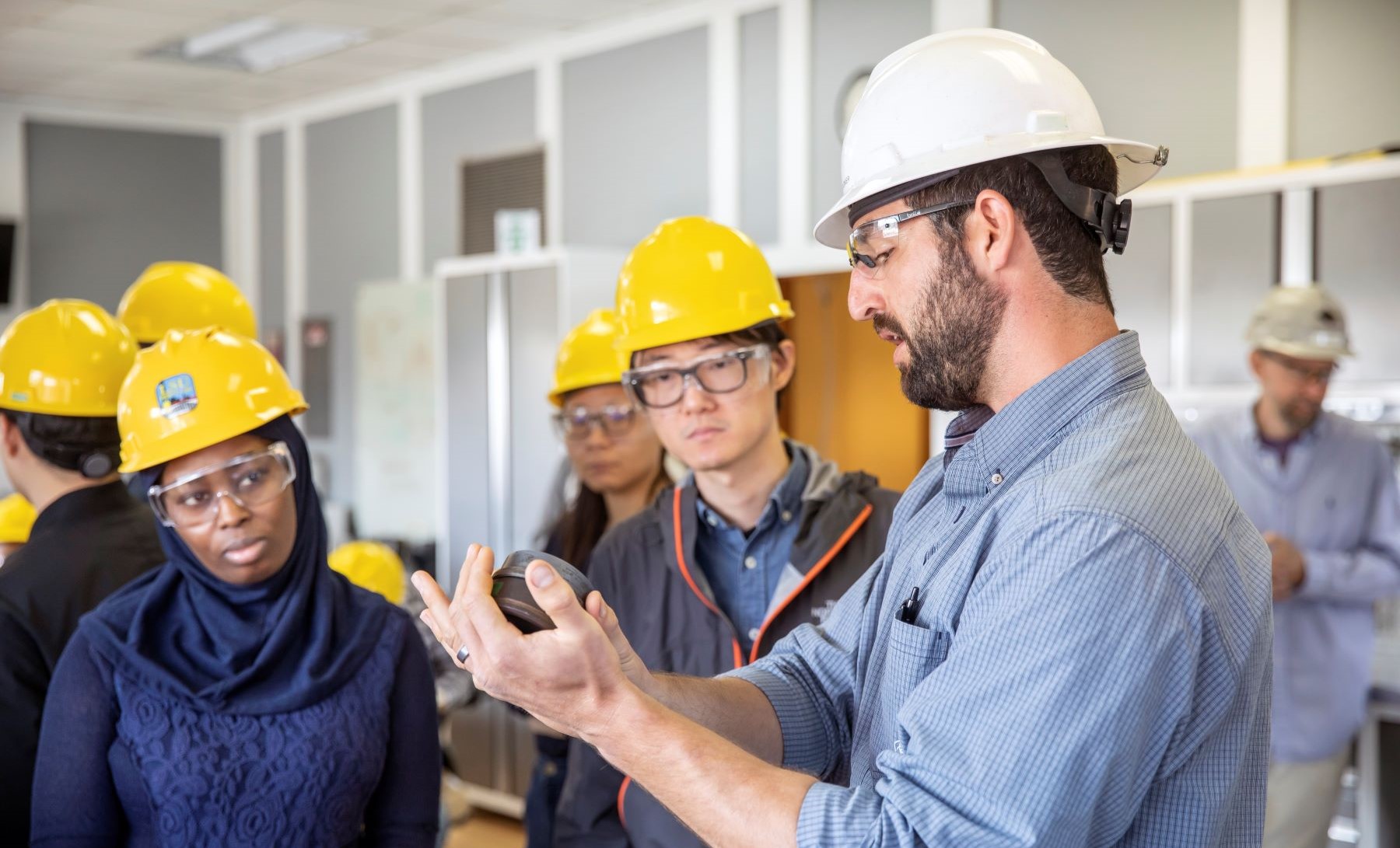 a classroom of students wearing hard hats learn from an engineering professor